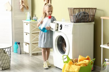 Küçük kız evde çamaşır yıkıyor.