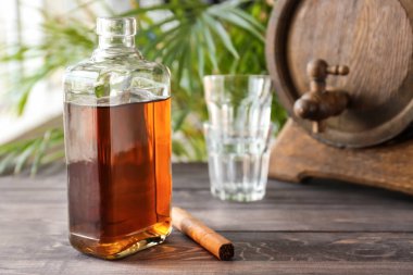 Ahşap masada puro ile bir şişe soğuk viski