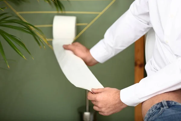 Homem arrancando papel higiênico em WC — Fotografia de Stock