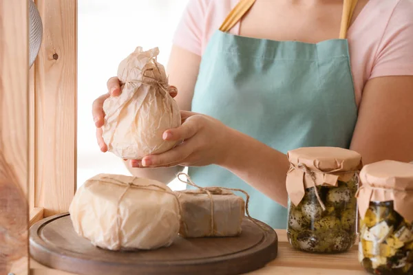 Vrouw controleren smakelijke kaas op plank in keuken — Stockfoto