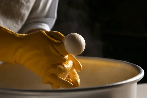 Femme préparant un fromage savoureux sur fond sombre — Photo