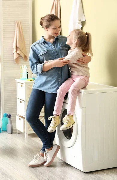 Jovem mulher e sua filha fazendo lavanderia em casa — Fotografia de Stock