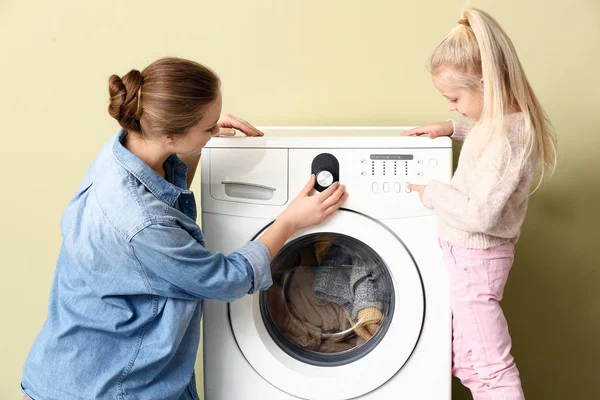 Молода жінка і її маленька дочка роблять прання вдома — стокове фото