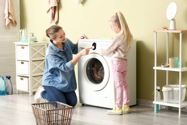 Jovem mulher e sua filha fazendo lavanderia em casa — Fotografia de Stock