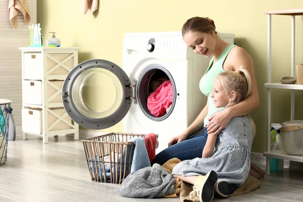 Jovem mulher e sua filha fazendo lavanderia em casa — Fotografia de Stock