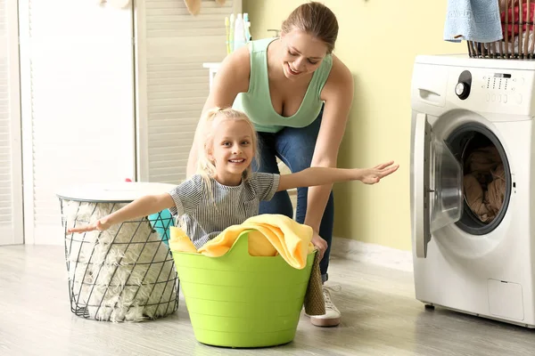 Νεαρή γυναίκα και η μικρή κόρη της παίζοντας ενώ κάνει μπουγάδα στο σπίτι — Φωτογραφία Αρχείου