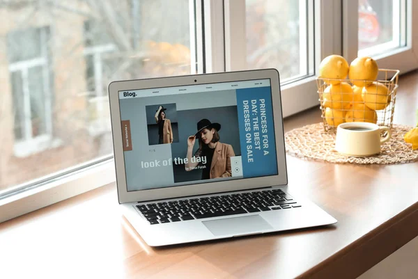 Laptop with open page of fashion blog on window sill