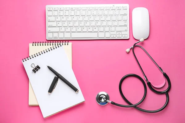 PC keyboard, mouse, stethoscope and stationery on color background