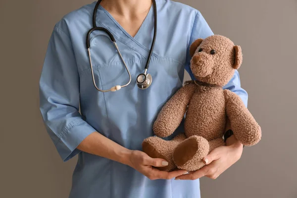 Педиатр с игрушечным медведем на цветном фоне — стоковое фото