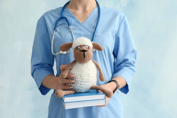 Pediatra z zabawkami owiec i książek na jasnym tle — Zdjęcie stockowe