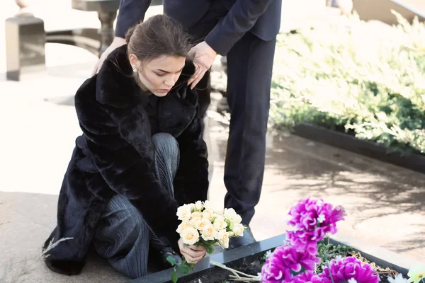 Paar zetten bloemen op het graf van hun familielid op de begrafenis — Stockfoto