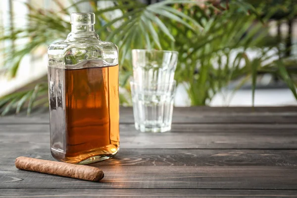 Bottle of cold whiskey with cigar on wooden table — Stock Photo, Image