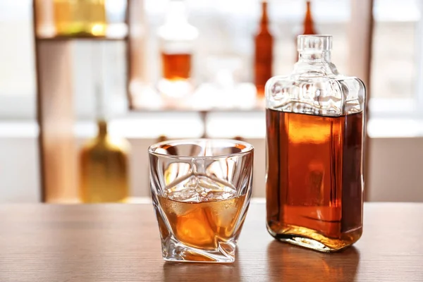 Glass and bottle of cold whiskey on table in bar — Stock Photo, Image