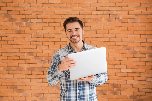 Manlig programmerare med laptop på tegel bakgrund — Stockfoto