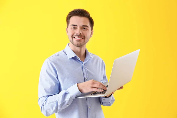 Männlicher Programmierer mit Laptop auf farbigem Hintergrund — Stockfoto