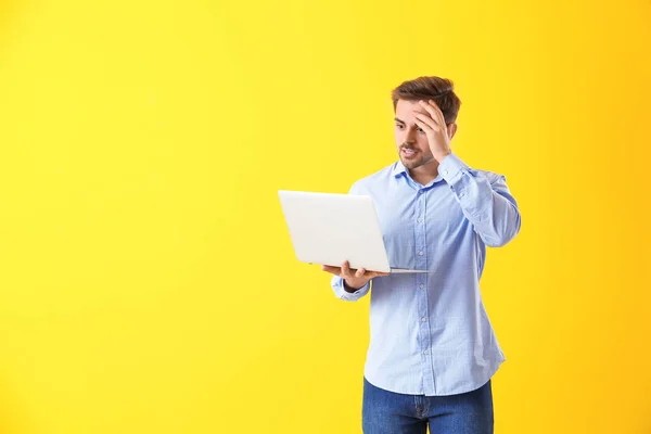 Programador masculino chocado com laptop em fundo de cor — Fotografia de Stock