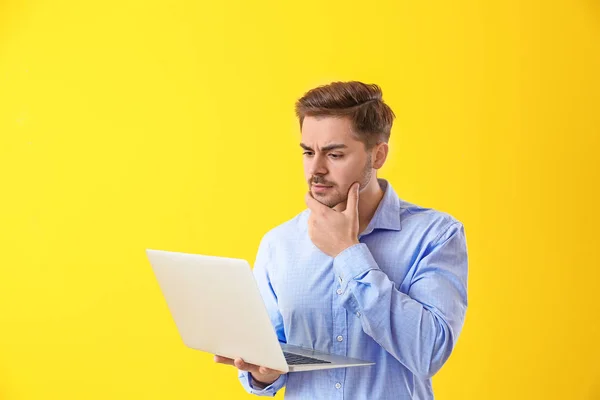 Tankeväckande manliga programmerare med laptop på färg bakgrund — Stockfoto