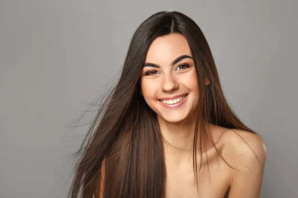 Gyönyörű fiatal nő portréja, hosszú hajú, szürke háttérrel — Stock Fotó
