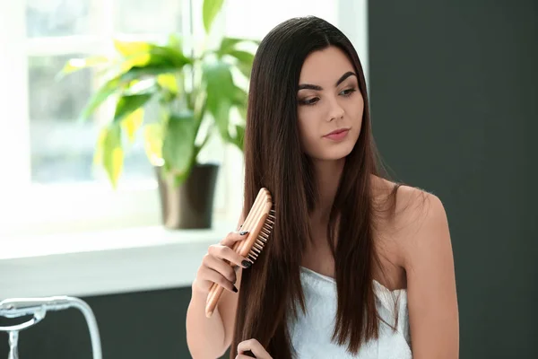 Vacker ung kvinna borsta hennes friska långt hår i Bad rummet — Stockfoto