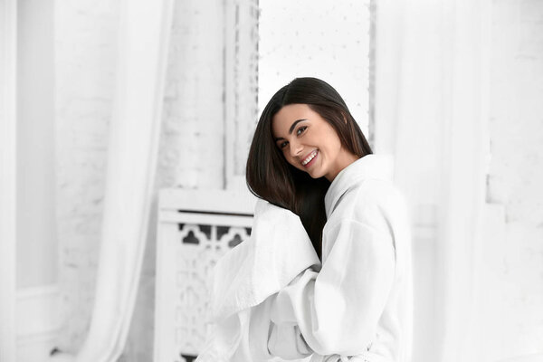 Красивая молодая женщина вытирает здоровые длинные волосы дома
