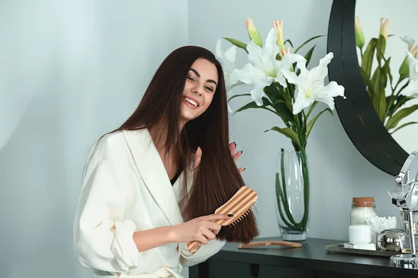 Beautiful young woman brushing her healthy long hair at home — Stock Photo, Image