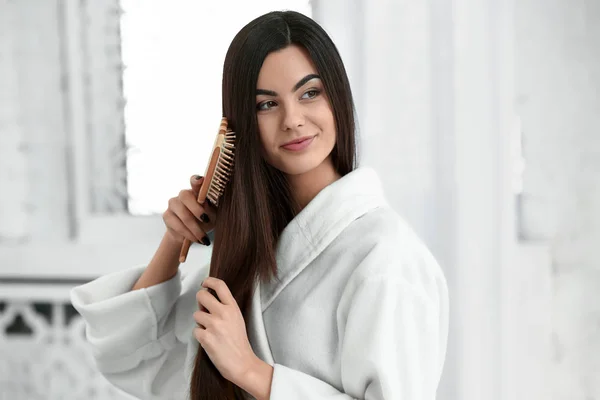 Beautiful young woman brushing her healthy long hair at home — Stock Photo, Image