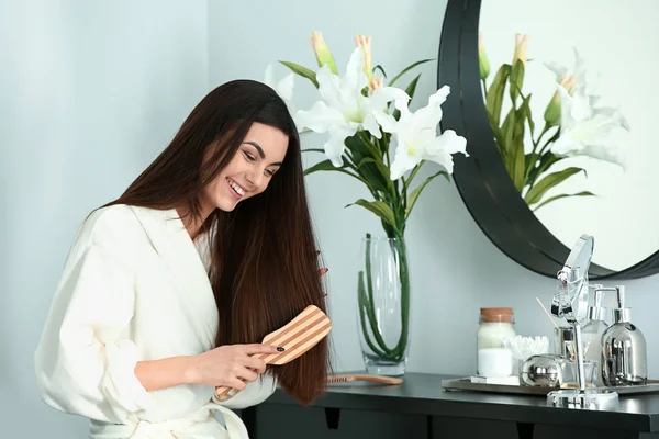 Hermosa mujer joven cepillando su cabello largo saludable en casa — Foto de Stock