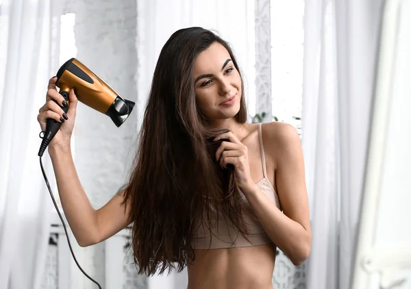 Gyönyörű fiatal nő szárítás neki egészséges, hosszú haj otthon — Stock Fotó