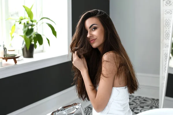 Beautiful young woman with healthy long in bathroom — Stock Photo, Image