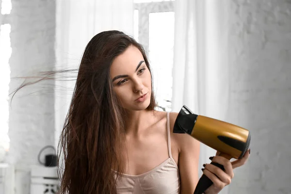 Mulher bonita secando seu cabelo longo saudável em casa — Fotografia de Stock