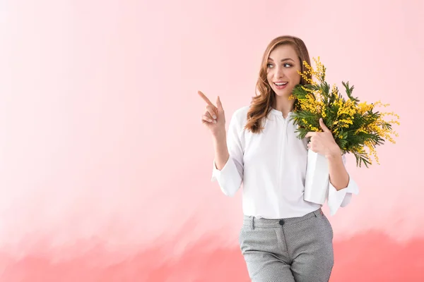 Beautiful young woman with bouquet of mimosa flowers on color background