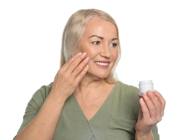 Mulher madura aplicando creme facial no fundo branco — Fotografia de Stock