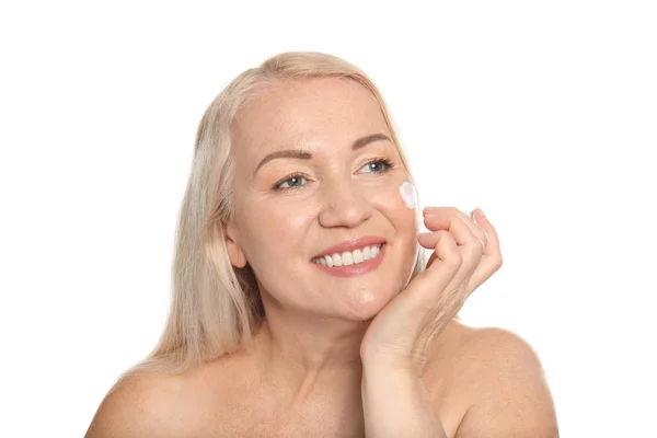 Mujer madura aplicando crema facial sobre fondo blanco — Foto de Stock