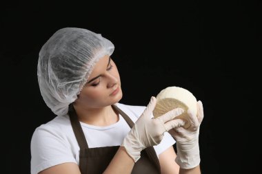 Woman holding tasty cheese on dark background clipart
