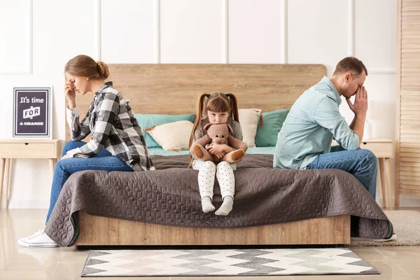 Sad family sitting on bed after quarrel