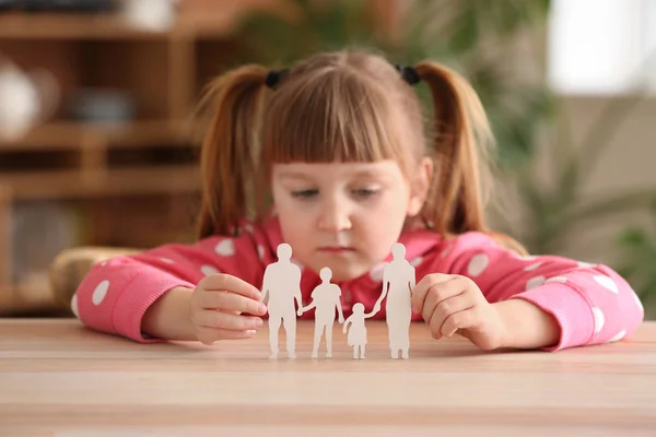 Sad little girl with figure of family at table. Concept of divorce — Stock Photo, Image