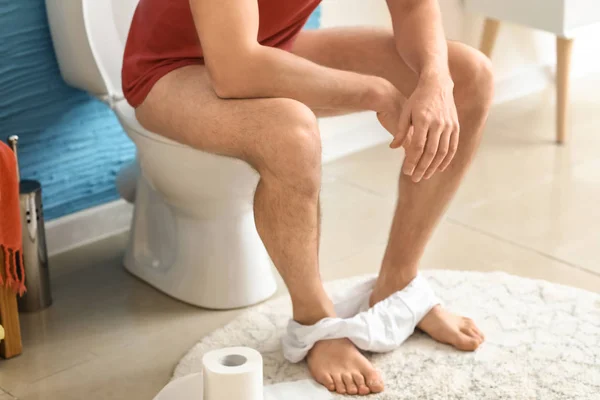 Homem sentado no vaso sanitário em casa — Fotografia de Stock