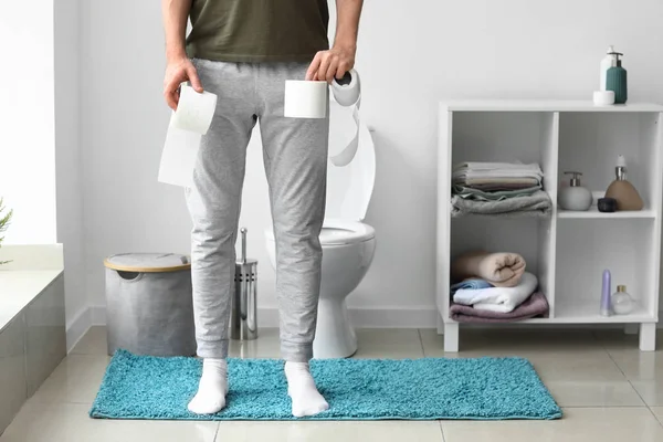 Человек с рулонами бумаги в туалете — стоковое фото