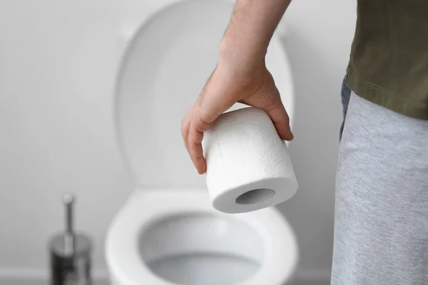 Man with roll of toilet paper in WC, closeup — Stock Photo, Image