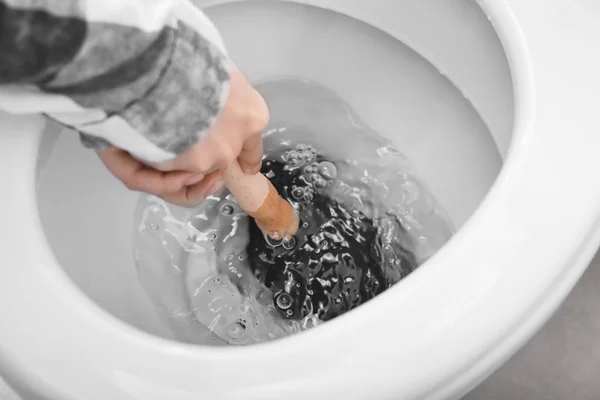 Jovem mulher usando êmbolo para desentupir um vaso sanitário — Fotografia de Stock