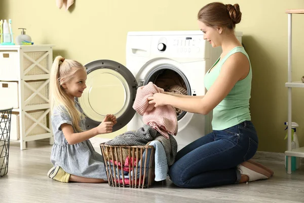 Jovem mulher e sua filha fazendo lavanderia em casa — Fotografia de Stock