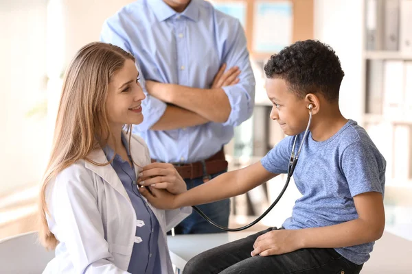 Педиатр показывает афроамериканскому мальчику, как пользоваться стетоскопом в клинике — стоковое фото