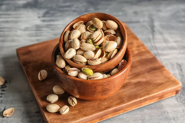 Schalen mit leckeren Pistazienkernen auf grauem Tisch — Stockfoto