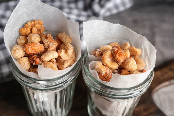 Jars with tasty sugared nuts on table, closeup — Stock Photo, Image