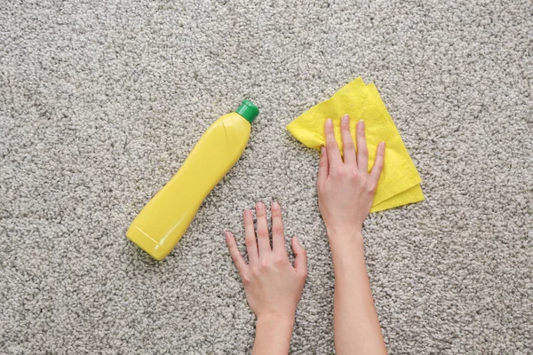 Mãos femininas com pano e detergente no tapete — Fotografia de Stock