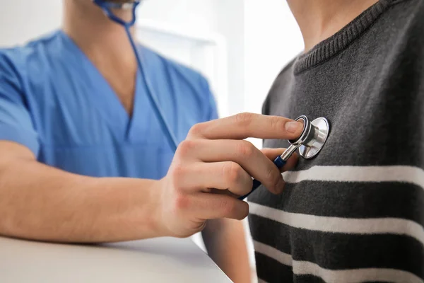 Male doctor listening heartbeat of female patient in clinic — Stock Photo, Image