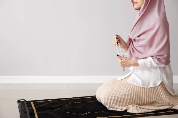 Muslimische Frau betet in der Nähe einer Lichtwand — Stockfoto
