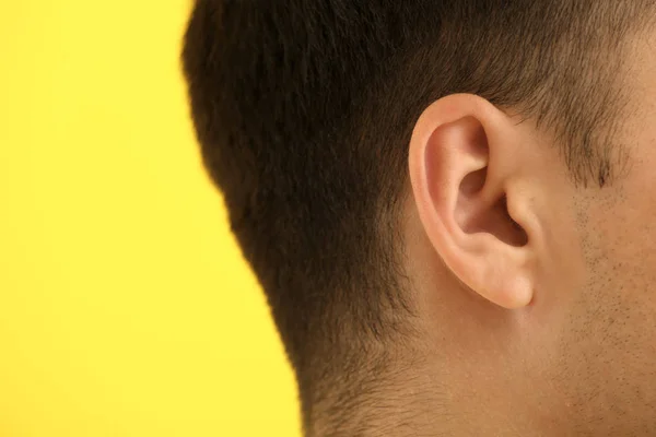 Hombre joven con problemas de audición en el fondo de color, primer plano —  Fotos de Stock