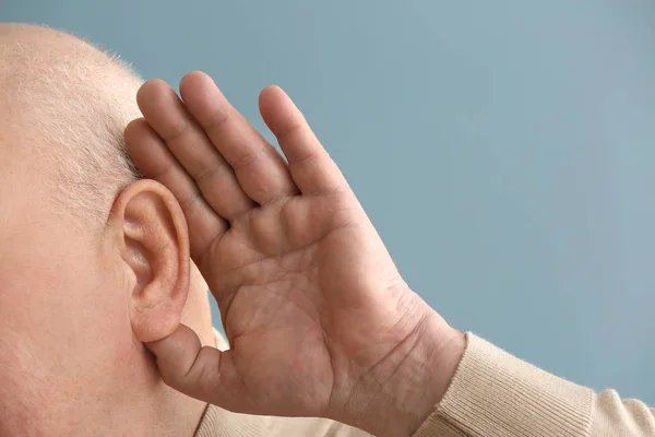 Senior man with hearing problem on color background, closeup — Stock Photo, Image