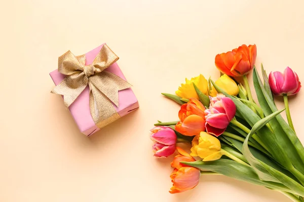 Beautiful tulip flowers with gift box on color background — Stock Photo, Image